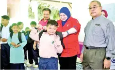  ??  ?? Deputy Works Minister Datuk Rosnah Rashid Sharlin (second right) who is also Papar member of parliament assisting a student with his school bag after handing over schooling needs contribute­d by North-South Expressway (PLUS) Malaysia Berhad at SK Tanaki...