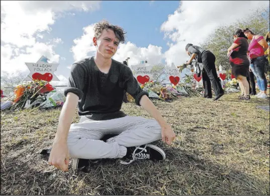  ?? Gerald Herbert The Associated Press ?? Senior Chris Grady of Marjory Stoneman Douglas High School sits at a Parkland, Fla., memorial days after the Feb. 14 shooting.