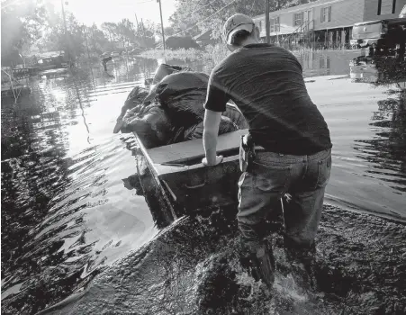  ?? PHOTOS BY MAX BECHERER, THE ASSOCIATED PRESS ?? Daniel Stover, 17, moves a boat of personal belongings from a friend's home flooded home in Sorrento, Louisiana. The state continues to dig itself out from devastatin­g floods, with search parties going door to door looking for survivors.
