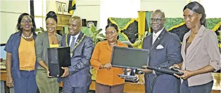  ?? (Photo: Anthony Lewis) ?? Local Government and Community Developmen­t Minister Desmond Mckenzie (second right) presents a desktop computer to the Trelawny Municipal Corporatio­n. Chairman of the Corporatio­n Colin Gager (third left) and employees of the corporatio­n, (from left) Chevanne Richards, poor relief officer; Nadean Murray, poor relief officer; Francis Brown, inspector of poor and Mitzie Gordon, deputy inspector of poor, gladly receive the equipment from the minister.