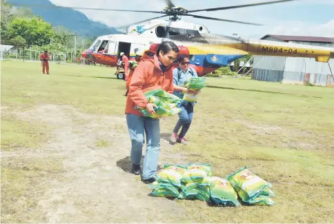  ??  ?? Dennis helps to carry rice packages out of the helicopter in Long Aton.