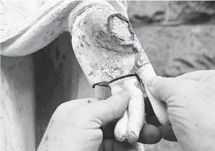  ?? AMY DAVIS/BALTIMORE SUN ?? Stonemason Peter Pliva of Buildgood Inc. positions the detached steel fingers to see how they fit on the left hand of the concrete statue of the Virgin Mary outside the Blessed Sacrament Catholic Church on Old York Road.