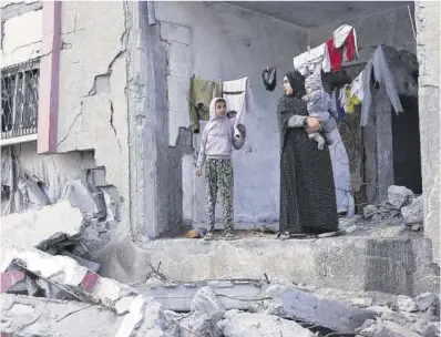  ?? Saleh Salem / Reuters ?? Una mujer junto a sus dos hijos en su casa semidestro­zada de Rafah.