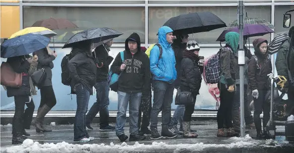  ?? NICK PROCAYLO/PNG ?? Soaked commuters wait for buses Thursday at the Commercial Street SkyTrain station after a wild week of weather.