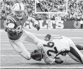  ?? AJ Mast / Associated Press ?? The Colts’ Jack Doyle, left, dives for the end zone to top off a 3-yard catch with a second-quarter score despite the best efforts of the Broncos’ Darian Stewart.