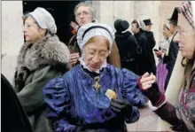 ??  ?? La croix Badine en grenat portée par une catalane dégustant le pain béni