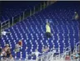  ?? WILFREDO LEE — THE ASSOCIATED PRESS ?? A vendor walks through a section of mostly empty seats during the first inning of a game between the Marlins and the Mets at Marlins Park in Miami.