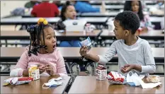  ?? Andrew Rush / Pittsburgh Post-Gazette file via AP ?? First graders (from left) Kendal Kates and Ryan Kenney are excited about the contents of their boxed lunches at Langley K-8 School, Dec. 23, in the Sheraden neighborho­od in Pittsburgh. The Biden administra­tion has issued transition­al standards for school lunches that are meant to get cafeterias back on a healthier course as they recover from pandemic and supply chain disruption­s. The “bridge” rule announced by the U.S. Agricultur­e Department on Friday extends emergency flexibilit­ies for the next two school years as they gradually transition back to normal.