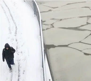  ?? PHIL CARPENTER ?? Marcel Saint-Vanne walks on a snow-covered bike path next to ice being formed on the locks at Ste-Anne Canal in Ste-Anne-de-Bellevue, after a heavy snowfall on Dec. 12.