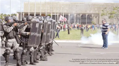  ?? — AFP ?? A protester stands in front of a line of riot police during the protest “Occupy Brasilia” against the labour and social security reforms and the government of President Michel Temer in Brasilia.