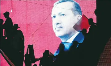  ?? (Baz Ratner/Reuters) ?? TURKISH SUPPORTERS are silhouette­d against a screen showing President Tayyip Erdogan during a progovernm­ent demonstrat­ion in Ankara on Sunday.