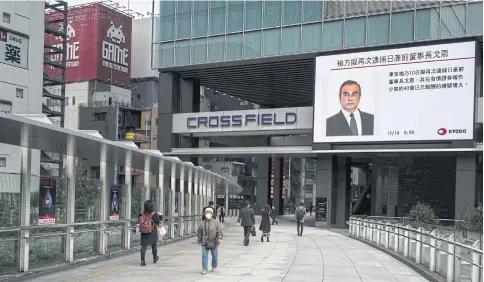  ?? AFP ?? Pedestrian­s walk past a television screen showing a news programme featuring former Nissan Motor Co chairman Carlos Ghosn in Tokyo yesterday.