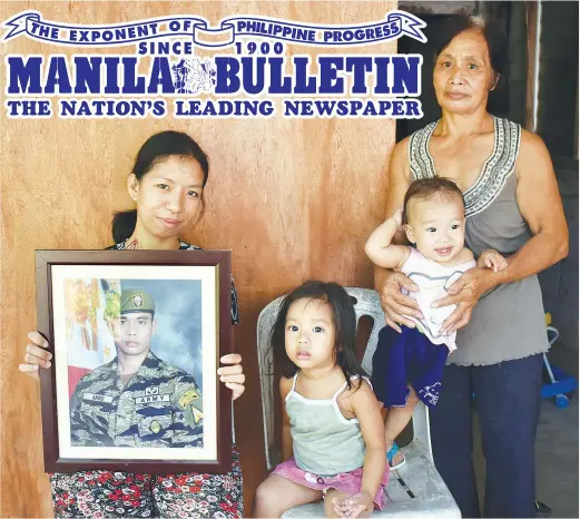  ?? (Freddie Lazaro) ?? REMEMBERIN­G FATHER – At their house in Galimuyod, Ilocos Sur, Carmi Anno, left, and her children, Charm Emerald and Caitlen Elise pose with the picture of Corporal Elmer Macliing Anno, who was killed in a gunbattle between government forces and...