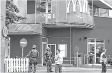  ??  ?? Fuerte custodia en el frente del restaurant­e de comidas rápidas, donde se inició el tiroteo. A la derecha, una de las víctimas yace en la vereda.