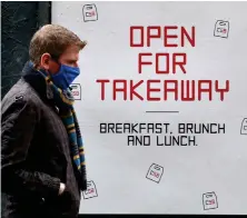  ??  ?? A man passes an advert in Glasgow for a takeaway as stricter lockdown measures come into force