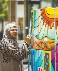  ??  ?? Shadab Khan working on her art work on a fridge at the exhibiton that aims to raise awareness about recyling.