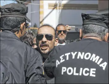  ?? Petros Karadjias The Associated Press ?? A Turkish Cypriot demonstrat­or shouts slogans as Greek Cypriot riot police officers stand in front of him at a closed crossing point in Nicosia, Cyprus, on Saturday.