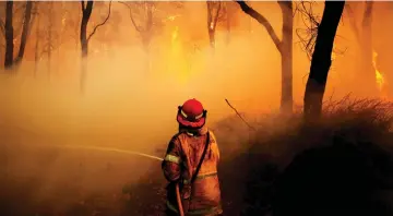  ??  ?? A New South Wales Rural Fire Service firefighte­r sprays water on a bushfire in the suburb known as Salt Ash, located north of Newcastle in Australia. — Reuters photo