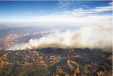  ?? Photos by Paul Chinn / The Chronicle ?? Above: Smoke from the Tubbs Fire rises high into the air as the firestorm continues to burn out of control. At right: Homes appear undamaged near others that burned to the ground in Santa Rosa’s Coffey Park neighborho­od.