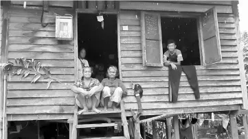  ?? — Photo by Wilfred Pilo ?? Uncertain future...Jimmy (sitting on the left) with Kanchi by her side, while Nanca stands on the left and Patrick looks out of the window of their dilapidate­d home at Kampung Remun Pelandok, some 10 km from Serian Town yesterday.