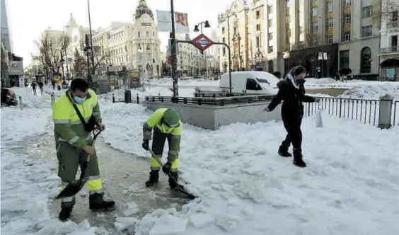  ?? EFE ?? ▶▶ Dos operarios retiran la nieve con palas en la Gran Vía de Madrid, durante ayer por la mañana.