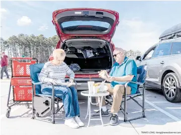  ?? TRAVIS LONG tlong@newsobserv­er.com ?? Cathy and Bob Stanton from Myrtle Beach, SC, picnic in the parking lot of Buc-ee’s in Florence, S.C.