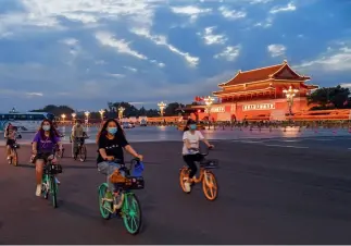  ?? Wei Yao ?? 19 de julio de 2022. Jóvenes conducen bicicletas compartida­s al pasar por la Plaza Tian’anmen en Beijing.