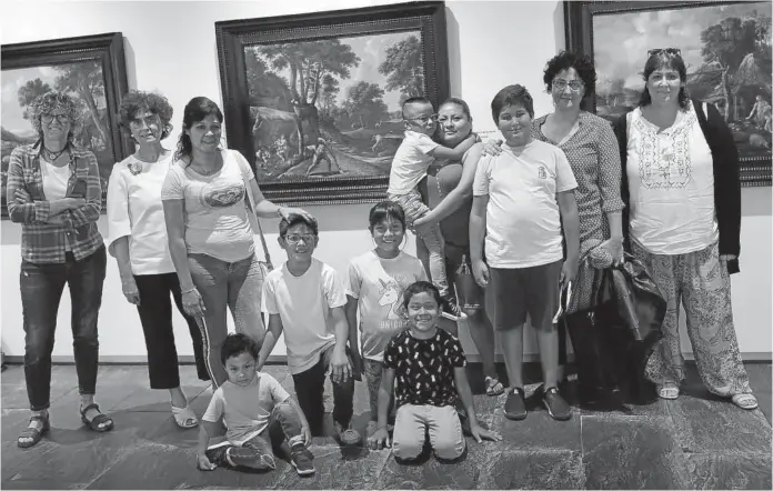  ??  ?? Eva Rada (i), la directora del Museo de Navarra Mercedes Jover (2i) y Loredana Agosta (2d), junto a algunos participan­tes en el proyecto y familiares; detrás, el cuadro escogido.