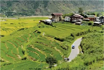  ??  ?? A car is pictured driving along a road amidst lush greenery in a valley of the Bhutanese town of Punakha. — AFP