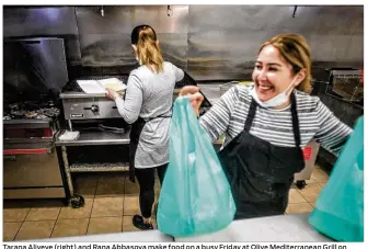  ??  ?? Tarana Aliyeve (right) and Rana Abbasova make food on a busy Friday at Olive Mediterran­ean Grill on West Third St. in Dayton. The restaurant, which moved from Northridge to downtown Dayton in 2018, saw revenues dip by as much as 30% in 2020.