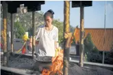  ??  ?? BELOW LEFT
Priest Huang Xingzhen,
30, removes used incense sticks from a burner at the temple.