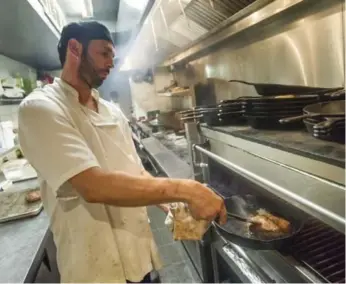 ?? J.P. MOCZULSKI/TORONTO STAR ?? Chef de cuisine Mike Erner works a pan at Jacobs & Co. Steakhouse in downtown Toronto.