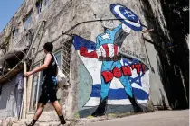  ?? AFP PHOTO ?? AMERICA’S CAPTAIN?
A man walks past a mural by the ‘Grafitiyul’ graffiti art group depicting United States President Joe Biden dressed as the Marvel comics character Captain America and standing before an Israeli flag and holding up his shield with the Star of David on it, on a street in the city of Tel Aviv, western Israel on Monday, April 15, 2024.