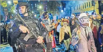  ?? AP ?? Armed police stand guard as defiant New Yorkers participat­e in a Halloween parade, hours after a truck attack killed eight people.