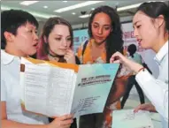  ?? XU WANGLIN / FOR CHINA DAILY ?? Two foreign students studying in Shanghai seek informatio­n about employment opportunit­ies at a job fair in Pudong New Area.