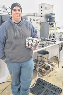  ?? CONTRIBUTE­D ?? Robert Sutton, one of the co-owners of Crooked Feeder Brewing in Cormack, holds a six pack of Crooked Feeder beer.