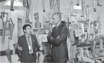  ?? CAROLYN KASTER, AP ?? Prosthetic­s hang behind President Obama as he tours the Cooperativ­e Orthotic and Prosthetic Enterprise ( COPE) Visitor Center in Vientiane, Laos, on Wednesday.