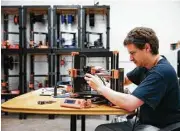  ??  ?? Cyclotroni­cs mechanical engineer Chris Kelley services a 3-D printer.