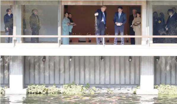  ?? — Reuters ?? US President Donald Trump and Japan’s Prime Minister Shinzo Abe feed carps before their working lunch at Akasaka Palace in Tokyo on Monday.