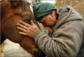  ?? AP PHOTO/JOHN LOCHER ?? Troy Miller rubs his horse Sally at his burned-out property in Concow, Calif. “I’ve got a lot of faith in God. I think things will be OK,” said Miller. “I have to tell my animals that.” A small group of residents who survived the deadly wildfire are defying evacuation orders and living in the burn zone.