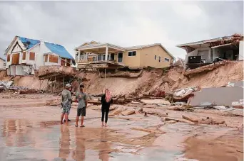  ?? Joe Raedle/Getty Images ?? Residents in Daytona Beach, Fla., examine damage to coastal homes in the aftermath of Hurricane Nicole, which came ashore early Thursday as a Category 1 storm before it weakened.