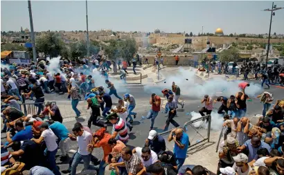  ?? AFP ?? Palestinia­n worshipper­s run for cover from teargas fired by Israeli forces in front of Al Aqsa mosque compound on Friday. —