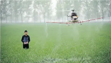  ?? A F P/G e t ty I m ag e s/ F i l e ?? A man uses a drone to spray pesticides on a farm in China. Use of the aerial devices is booming.