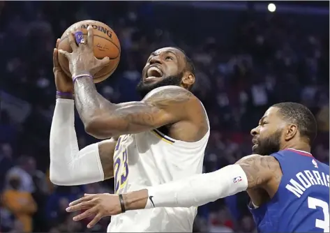  ?? AP file photo ?? LeBron James of the Lakers shoots as Clippers forward Marcus Morris Sr. defends during a game on March 8. The Lakers and Clippers will face off on July 30, the second game of a twin bill on the first day of NBA’s restart.