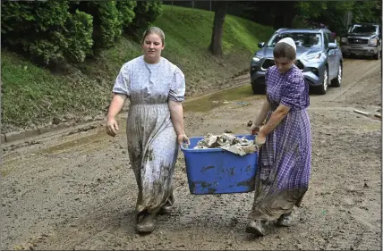  ?? PHOTOGRAPH­S BY TIMOTHY D. EASLEY — THE ASSOCIATED PRESS ?? Volunteers from the local Mennonite community carry tubfulls of debris from flood-soaked houses for disposal at Ogden Hollar in Hindman, Ky., on Saturday.