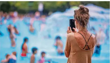  ?? FOTO: JENS BÜTTNER/ZB/DPA ?? Eine Jugendlich­e fotografie­rt mit ihrem Handy in einem Berliner Schwimmbad. Hunderttau­sende folgen minderjähr­igen Influencer­n auf Youtube, Instagram und Tiktok durch deren Alltag.