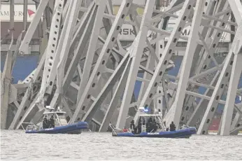  ?? ?? Police boats on Wednesday work around the cargo ship that is stuck under part of the structure of the Francis Scott Key Bridge in Baltimore after the ship hit the bridge. STEVE HELBER/AP
