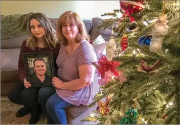  ?? Austin Dave/The Signal ?? Katie and Angela Romero hold a photo of Richard Romero near their family’s Christmas tree on Thursday. 50-year-old Richard Romero was heading back home from taking a class at College of the Canyons when he collided with Kimberlee Paniza’s 2006 Chrysler...