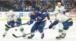  ?? CHRIS O’MEARA/AP ?? Brayden Point (21) slips between Vancouver Canucks center Bo Horvat (53) and defenseman Luke Schenn (2) on Thursday.