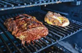  ?? Photos by William Luther / Staff photograph­er ?? Smoked Herbed Mayonnaise Pork Roast and chicken breasts come off the grill. How much of the taste of binders transfers to meat depends on its cooking time.